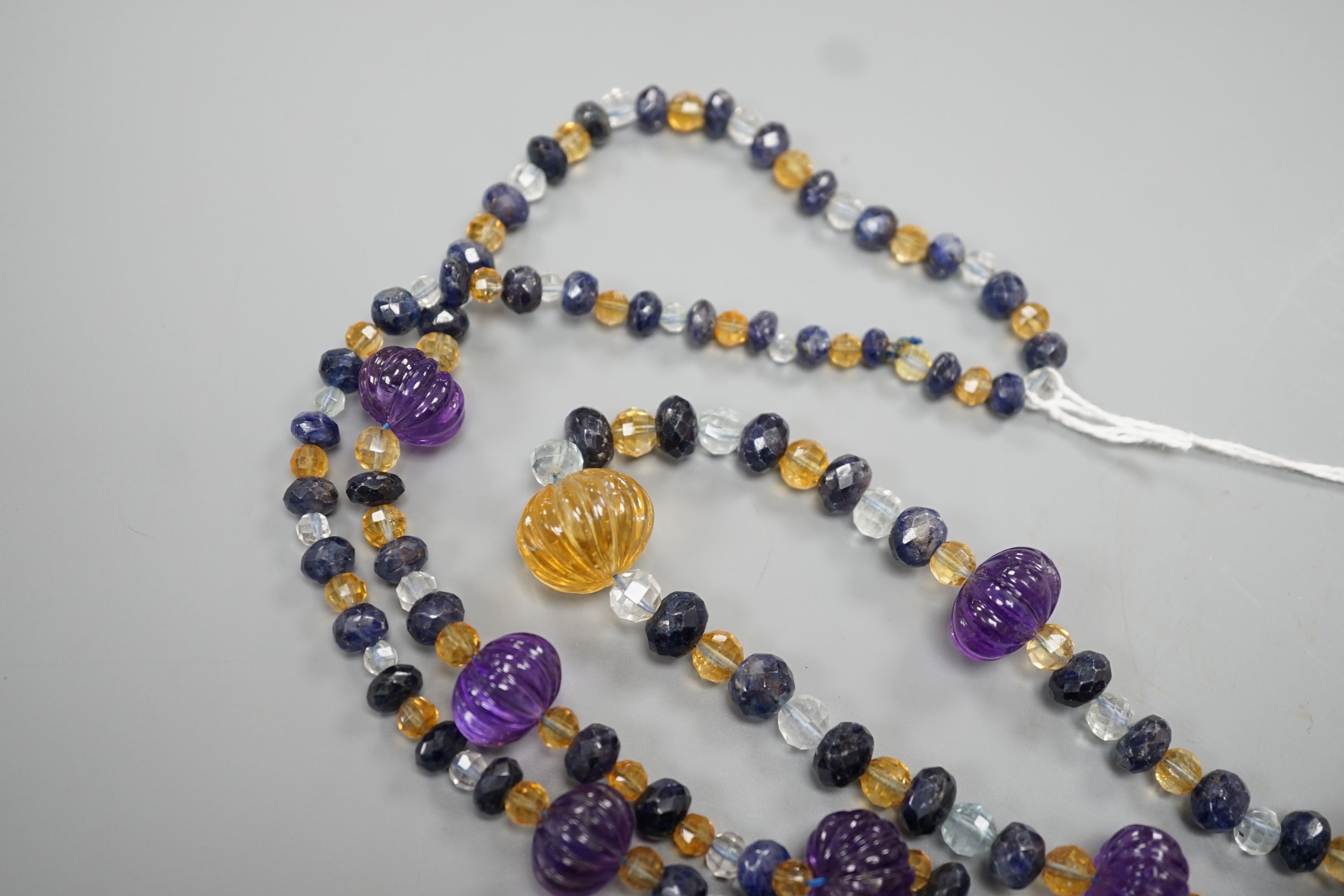 A modern single strand fluted amethyst and facet cut sapphire, citrine and aquamarine bead set necklace, 134cm.